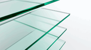 Placas de vidro transparente empilhadas em camadas, vistas em perspectiva, com bordas verdes refletindo a luz.