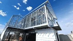 Estrutura em light steel frame de um prédio em construção, com perfis metálicos aparentes sob céu azul com algumas nuvens.
