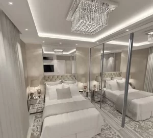 Espelhos na Decoração de quarto moderno com paredes espelhadas, cama estofada em tons claros, iluminação embutida no teto e lustre de cristal, criando sensação de amplitude e sofisticação.